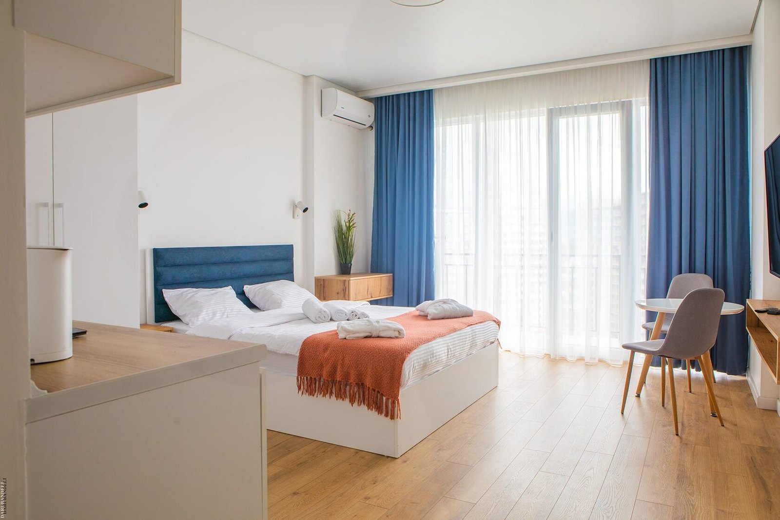 NEXT Orange: Furnished studio at NEXT Orange with blue curtains and an orange bed throw