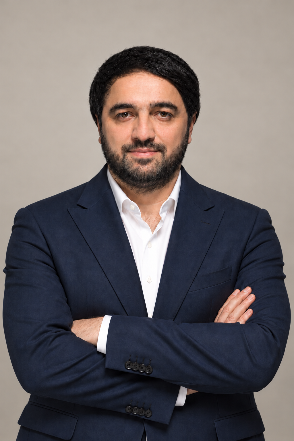 Kakha Devadze, Founder of NEXT, wearing a navy suit and white shirt against a warm beige-grey studio background; digitally styled for this presentation